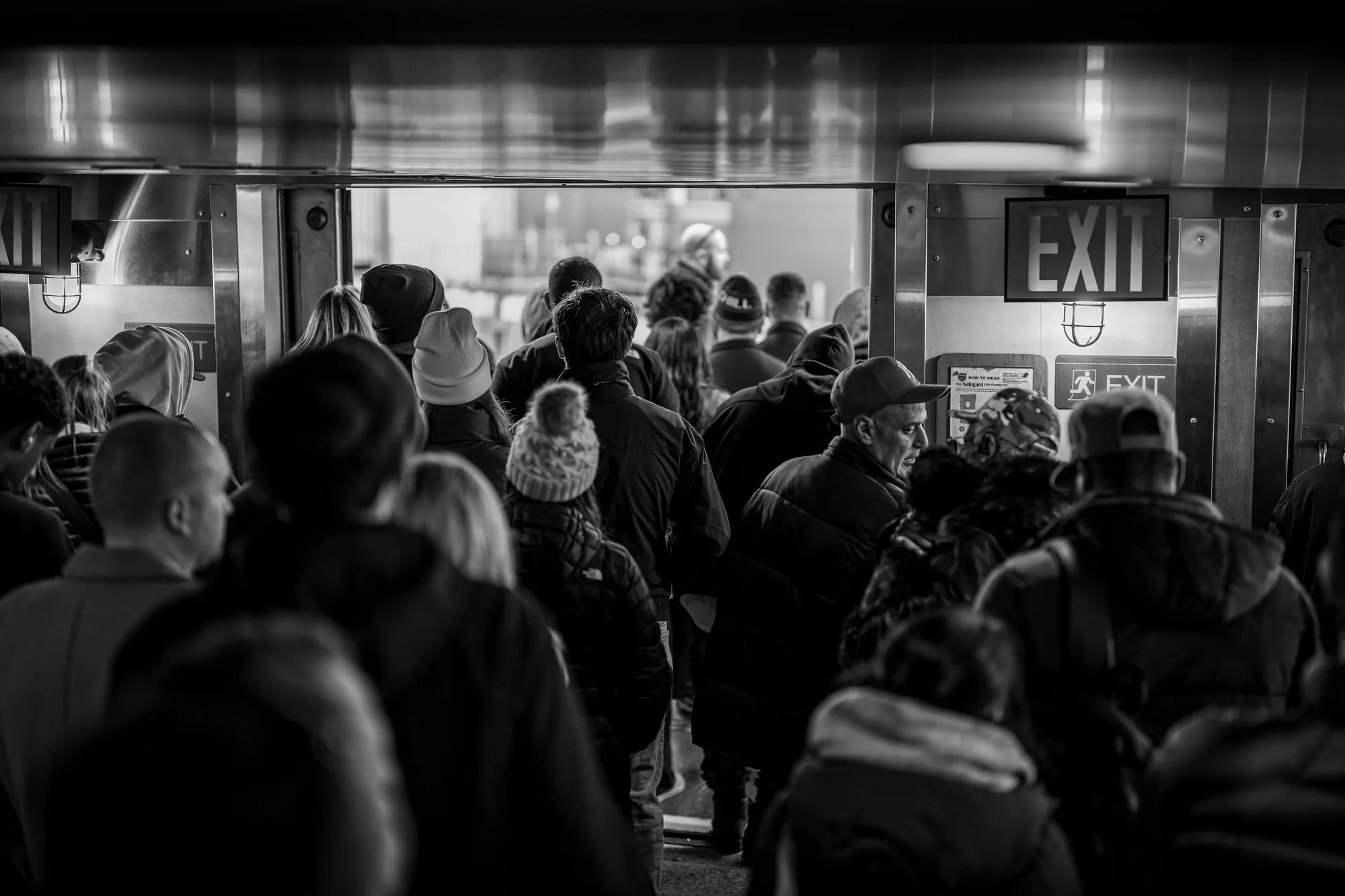 A public crowd moving through an exit, seen as a field of attention and circulation.